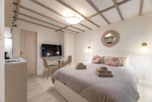 a white bedroom with a bed with towels on it at Villa Caron - Studios haut de gamme hyper centre in Rouen