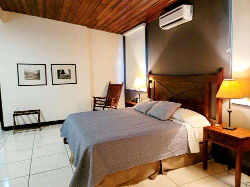 a bedroom with a bed and two chairs and a fan at Hotel Casa del Sol in Managua