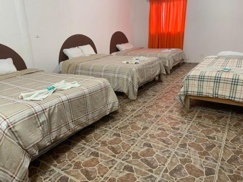 três camas sentadas num quarto com piso em HOTEL PUERTO REAL em Paraíso