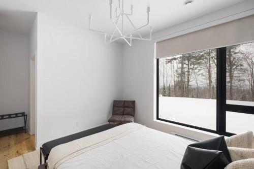 a bedroom with a bed and a large window at Chalet Peak Tremblant: Your Mountain Escape. in La Conception