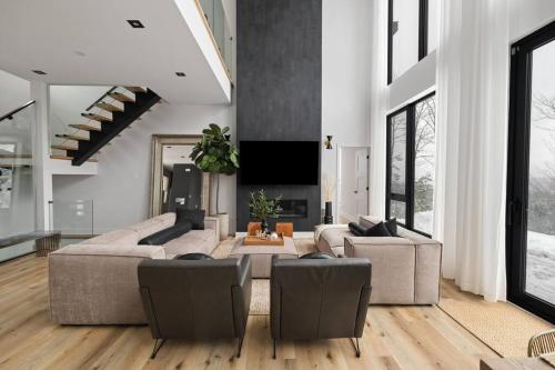 a living room with two couches and a flat screen tv at Chalet Peak Tremblant: Your Mountain Escape. in La Conception