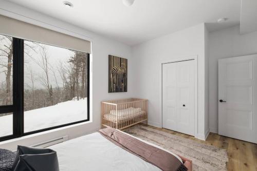 a bedroom with a bed and a large window at Chalet Peak Tremblant: Your Mountain Escape. in La Conception