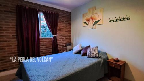 1 dormitorio con cama con sábanas azules y ventana en "La Perla del Volcán" en El Volcán