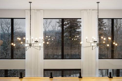 a dining room with windows and a chandelier at Chalet Peak Tremblant: Your Mountain Escape. in La Conception
