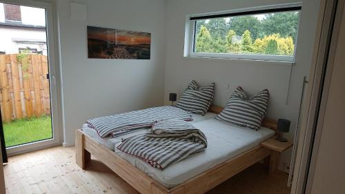 ein Schlafzimmer mit einem Bett mit Kissen und einem Fenster in der Unterkunft Ökohaus Spaden in Schiffdorf