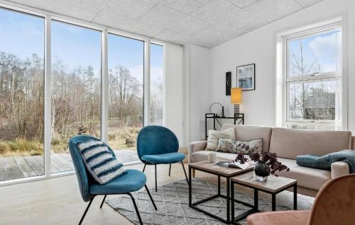 Cozy Home In Aakirkeby With Kitchen في Vester Sømarken: غرفة معيشة مع أريكة وكراسي ونوافذ