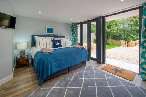 - une chambre avec un lit bleu et une porte coulissante en verre dans l'établissement Rotherwood, Gurnard Seafront, à Gurnard