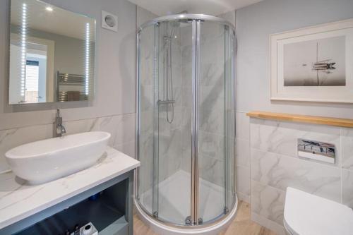 La salle de bains est pourvue d'une douche en verre et d'un lavabo. dans l'établissement Rotherwood, Gurnard Seafront, à Gurnard