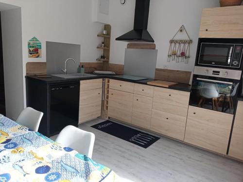a kitchen with wooden cabinets and a black appliances at Ty-Reviens in Lanrivoaré