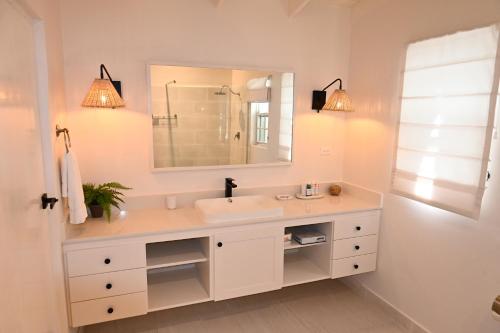 a white bathroom with a sink and a mirror at Little Good Harbour in Saint Peter