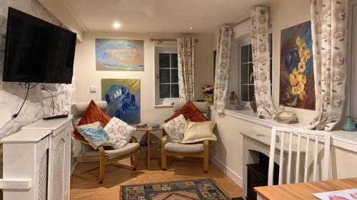 a living room with a table and chairs and a television at Cozy Cottage - Near Brew Pub / Snowdonia National Park. in Caernarfon