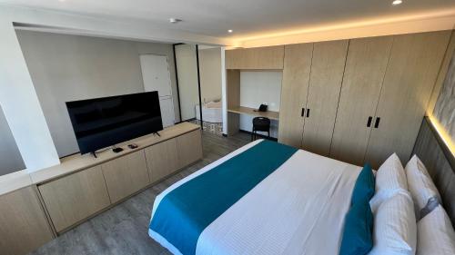 a bedroom with a large bed and a flat screen tv at Hotel Grand Park in Bogotá