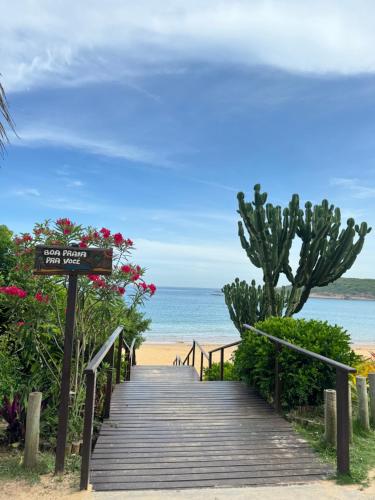 a wooden path to the beach with a sign at Enseada Azul - Apto 150m da Praia de Peracanga in Guarapari