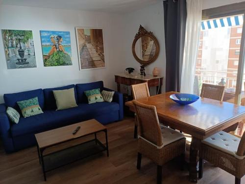 Una sala de estar con un sofá azul y una mesa. en Apartamento al lado de Barcelona y la playa, en Montgat