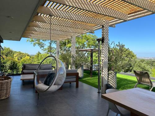 a patio with a swing and a table and chairs at Constantia View Apartments- Luxury Self Catering in Cape Town