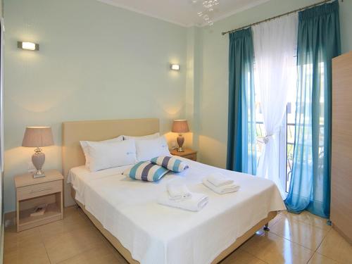 a bedroom with a large white bed with blue curtains at Kaplanis House in Neos Marmaras