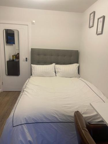 a bedroom with a large bed with white sheets at Private En-suite in Birmingham