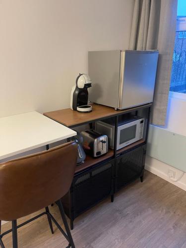 a desk with a microwave and a table with a chair at Private En-suite in Birmingham