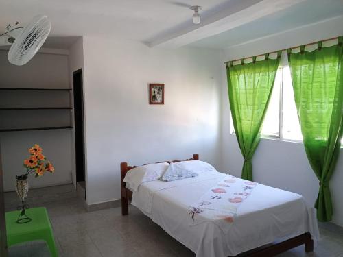Schlafzimmer mit einem Bett und einem Fenster mit grünen Vorhängen in der Unterkunft Hostal Adrimar in Bahía Solano