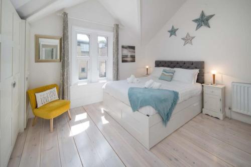 een witte slaapkamer met een bed en een stoel bij Solent View, 3bed apartment, fantastic sea views in West Cowes