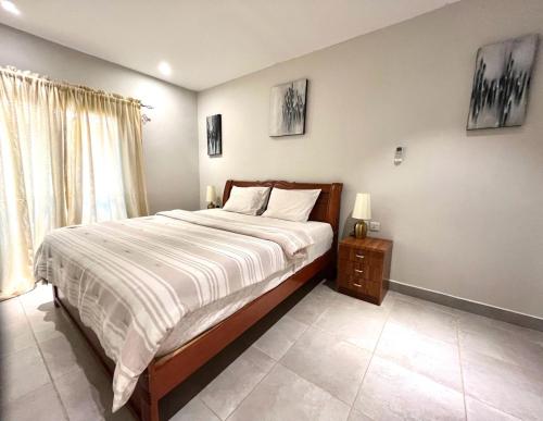 a bedroom with a large bed and a night stand at FOREST VIEW LUXURY APARTMENT in 3mins walk to beach pool view wifi in Kololi