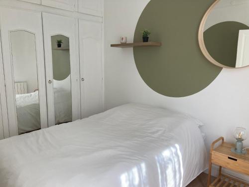 Schlafzimmer mit einem weißen Bett und einem Spiegel in der Unterkunft Appartement Saint-Denis Stade de France in Saint-Denis