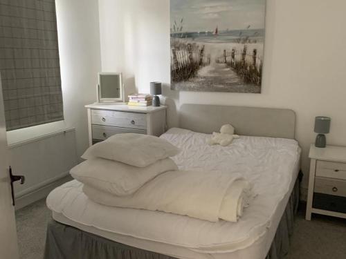 a white bed with a stuffed animal sitting on top of it at Captivating 3-Bed Cottage in Port na Blagh in Port na Bláiche