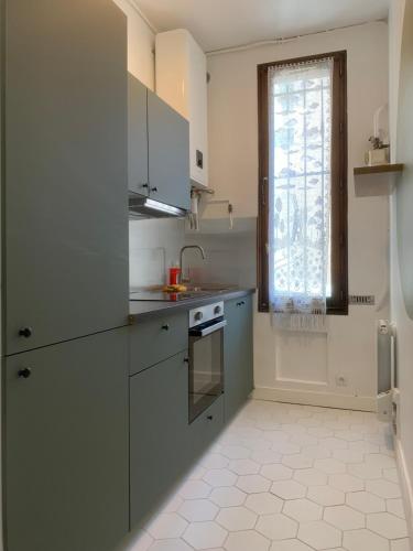 eine Küche mit weißen Schränken, einem Waschbecken und einem Fenster in der Unterkunft Appartement Saint-Denis Stade de France in Saint-Denis