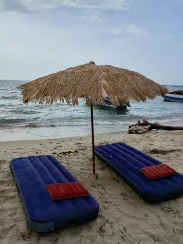 Dos sillas de playa azules bajo una sombrilla en la playa en Canadian House Rincón del Mar, en Rincón