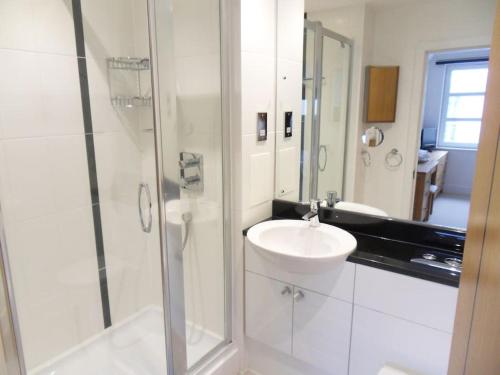 uma casa de banho branca com um lavatório e um chuveiro em Spinnaker apartment, 3bed with incredible views em East Cowes