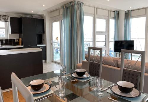 uma cozinha e sala de estar com uma mesa de vidro e cadeiras em Spinnaker apartment, 3bed with incredible views em East Cowes