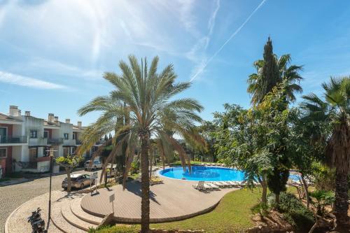 a resort with a swimming pool and palm trees at Host Wise - Deluxe Spacious House with Terrace & Jacuzzi in Portimão