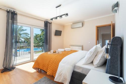 ein Schlafzimmer mit einem großen Bett und einem großen Fenster in der Unterkunft Deluxe Spacious House with Terrace & Jacuzzi in Portimão
