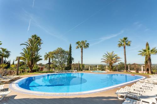 a large swimming pool with chairs and palm trees at Host Wise - Deluxe Spacious House with Terrace & Jacuzzi in Portimão