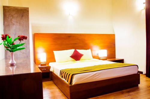 a bedroom with a bed and a vase with flowers at Roshara Nalla in Giriulla