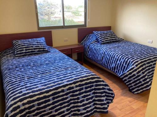 2 Betten nebeneinander in einem Zimmer in der Unterkunft Hostal Enerugi in Calama