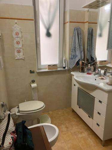 een badkamer met een toilet, een wastafel en een spiegel bij A due passi dal mare in Loano