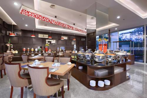 a restaurant with tables and chairs and a bar at Aston Lampung City Hotel in Bandar Lampung