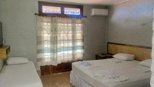 two beds in a room with a window at Pousada Villa Kite Flecheiras in Trairi