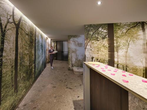 a person walking through a bathroom with paintings on the walls at Collina Luxury Relais in Clusone