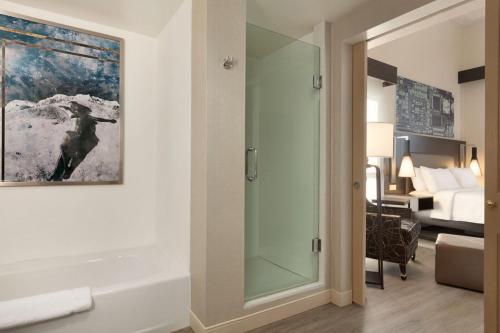 a bathroom with a glass shower and a bedroom at Hilton Garden Inn Cupertino in Cupertino