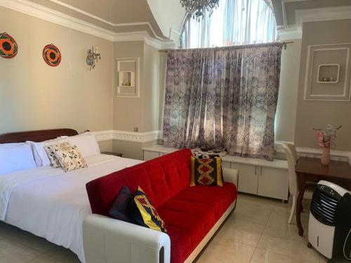 een slaapkamer met een rode bank en een raam bij Ayonthoo! in Lilongwe