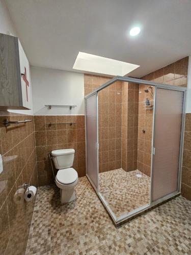 uma casa de banho com um WC e uma cabina de duche em vidro. em Sensity Home habitación elegante em Tehuacán