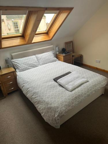 a bedroom with a bed with a white comforter and two windows at 30 College Street, Buckhaven, Leven, Fife, KY81JX in Buckhaven