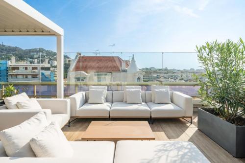 un salon avec des canapés blancs sur un balcon dans l'établissement Sublime 3 bedroom with roof terrace, à Cannes