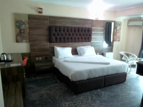 a bedroom with a large bed with a wooden headboard at Desikok Royal Hotel LTD in Port Harcourt