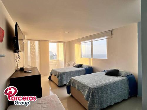 a hotel room with two beds and a television at Acogedor Apartamento Para Grupos Cerca Al Mar Por Parceros Group in Cartagena de Indias
