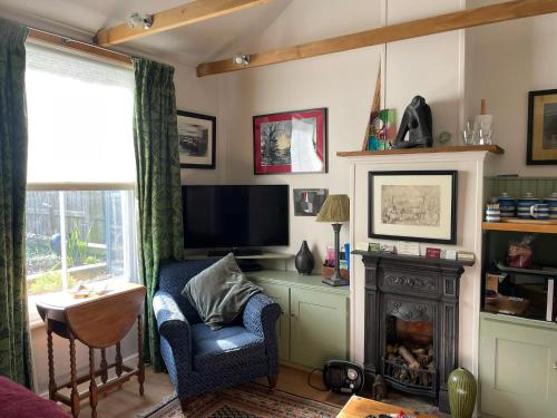 a living room with a tv and a chair and a fireplace at Little House Felixstowe in Felixstowe