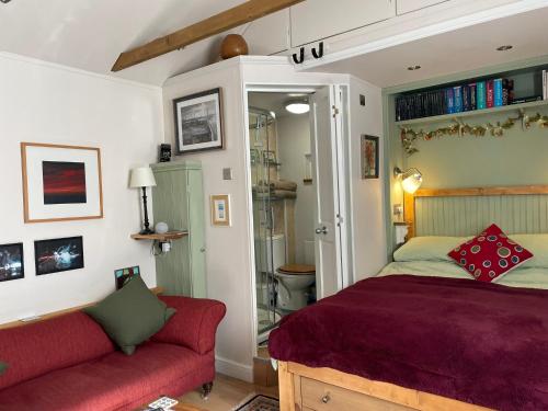 1 dormitorio con 1 cama y 1 sofá rojo en Little House Felixstowe, en Felixstowe