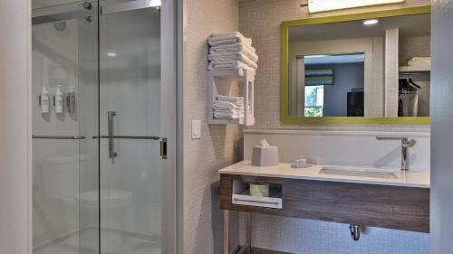 a bathroom with a shower and a sink and a mirror at Hampton Inn & Suites Keene in Keene